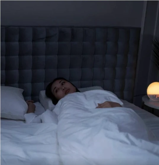 Pessoa acordada na cama durante a noite, em uma cena que representa preocupação